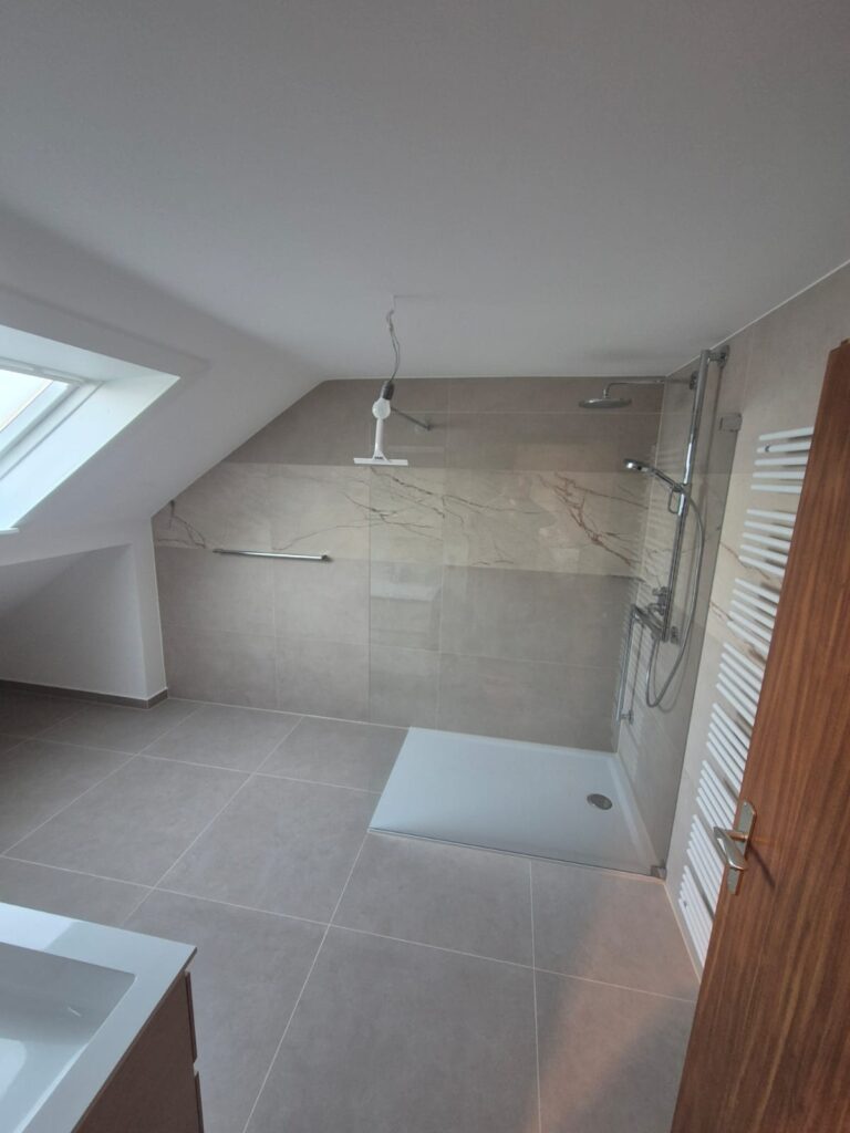 Neuer Duschbereich mit eleganten beigefarbenen Großformatfliesen als Teil einer umfassenden Badrenovierung