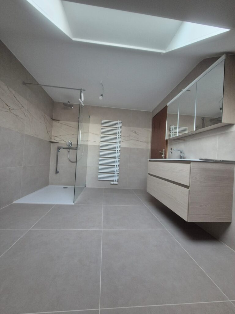 Hochwertige komplette Badgestaltung mit warmen beige Fliesen und neuem Duschbereich